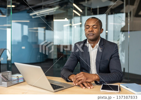 Adult person sitting calmly at a desk with a laptop and phone, practicing mindfulness and deep breathing to manage stress, find focus, and promote relaxation in a professional workplace environment Adult person sitting calmly at a desk with a laptop and phone, practicing mindfulness and deep breathing to manage stress, find focus, and promote relaxation in a professional workplace environment 137387833