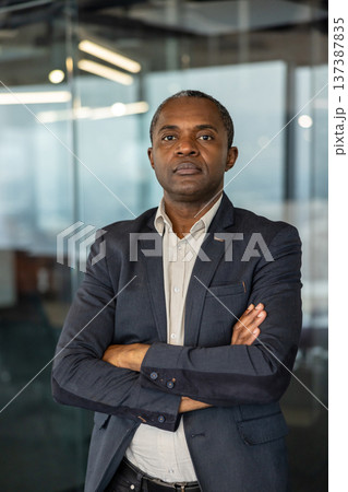 Experienced professional man standing with arms crossed, conveying confidence and authority in a modern office environment, symbolizing leadership and success in business Experienced professional man standing with arms crossed, conveying confidence and authority in a modern office environment, symbolizing leadership and success in business 137387835