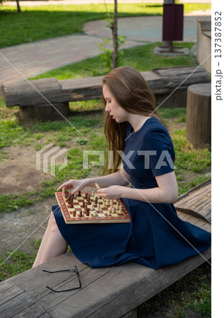 Caucasian woman playing chess outdoors. Caucasian woman playing chess outdoors. 137387852