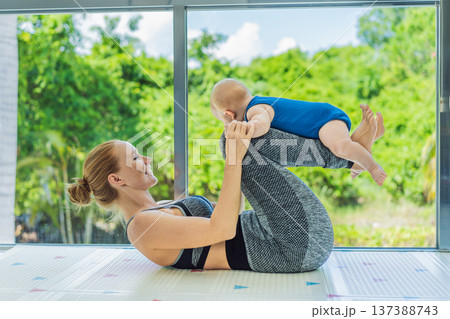 Mother doing fitness exercises while holding her baby at home, combining workout and childcare. Real lifestyle moment showing balance, strength and love. Postpartum fitness, healthy motherhood and Mother doing fitness exercises while holding her baby at home, combining workout and childcare. Real lifestyle moment showing balance, strength and love. Postpartum fitness, healthy motherhood and 137388743