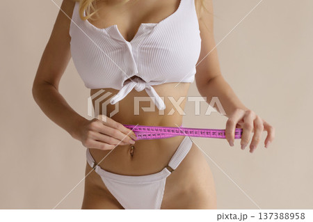 Slim female body with measuring tape around waist and hips, body care, weight loss and fitness diet concept 137388958
