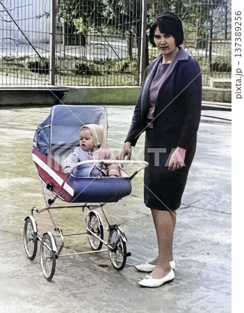 Vintage portrait of a mother and baby in a stroller. Young woman on a walk with a small child. Retro 1968. 137389256