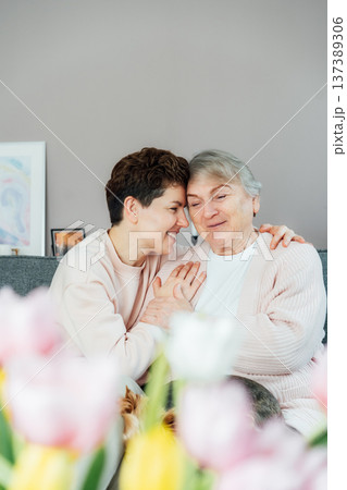 Emotional Adult daughter hugging happy senior 70s mother in cozy interior. Mother day. Happy family enjoying weekend together. Parenting love, care, generations unity. Spending time in retiring house 137389306