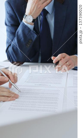 Businesspeople hands with pens reviewing documents and engaging in a discussion across a table, representing contract signing, legal consultation, negotiation, and important agreement collaboration Businesspeople hands with pens reviewing documents and engaging in a discussion across a table, representing contract signing, legal consultation, negotiation, and important agreement collaboration 137390020