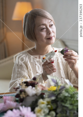 リビングで趣味のフラワーアレンジメントを作るシニア女性 137390263