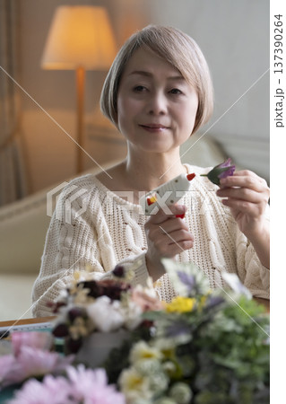 リビングで趣味のフラワーアレンジメントを作るシニア女性 137390264