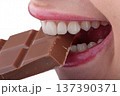 Close up of female mouth biting chocolate highlighting aesthetic ceramic veneers and perfect smile 137390371