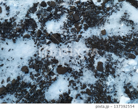 Dark earth texture with scattered snow. Winter soil background 137392554