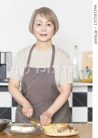 キッチンで野菜を切り料理の下ごしらえをするシニア女性 137393344