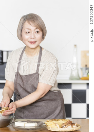 キッチンで野菜を切り料理の下ごしらえをするシニア女性 キッチンで野菜を切り料理の下ごしらえをするシニア女性 137393347