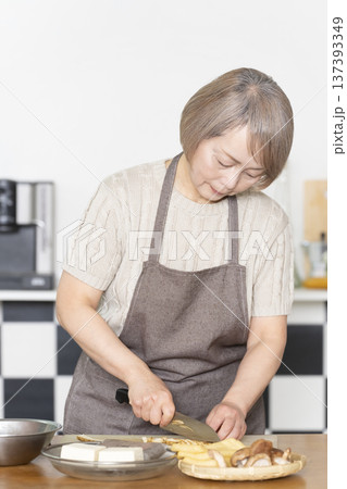 キッチンで野菜を切り料理の下ごしらえをするシニア女性 137393349