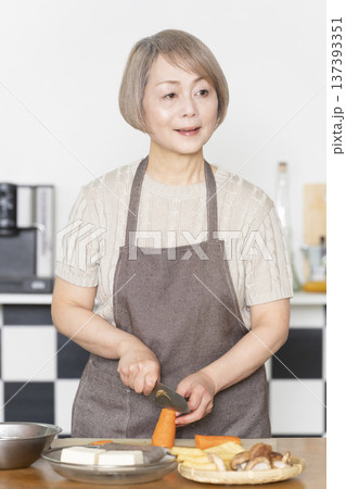 キッチンで野菜を切り料理の下ごしらえをするシニア女性 キッチンで野菜を切り料理の下ごしらえをするシニア女性 137393351