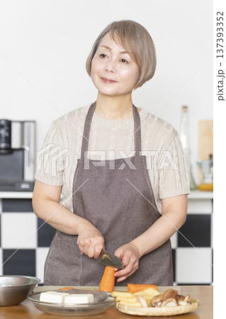 キッチンで野菜を切り料理の下ごしらえをするシニア女性 137393352