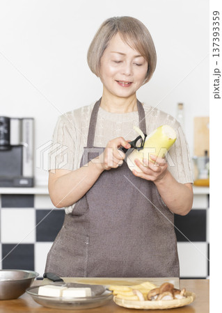 キッチンで野菜を切り料理の下ごしらえをするシニア女性 137393359