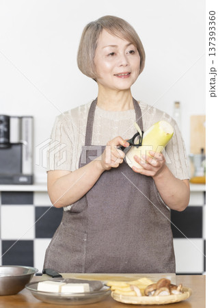 キッチンで野菜を切り料理の下ごしらえをするシニア女性 137393360