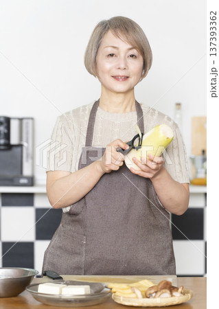 キッチンで野菜を切り料理の下ごしらえをするシニア女性 137393362