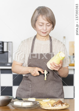 キッチンで野菜を切り料理の下ごしらえをするシニア女性 キッチンで野菜を切り料理の下ごしらえをするシニア女性 137393363