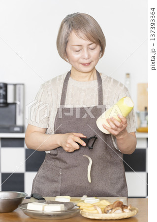 キッチンで野菜を切り料理の下ごしらえをするシニア女性 137393364