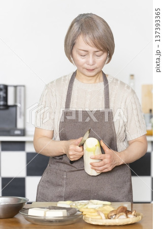 キッチンで野菜を切り料理の下ごしらえをするシニア女性 キッチンで野菜を切り料理の下ごしらえをするシニア女性 137393365
