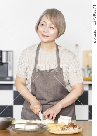 キッチンで野菜を切り料理の下ごしらえをするシニア女性 137393371