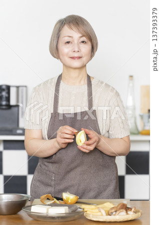 キッチンで野菜を切り料理の下ごしらえをするシニア女性 137393379