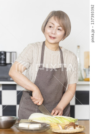 キッチンで野菜を切り料理の下ごしらえをするシニア女性 137393392
