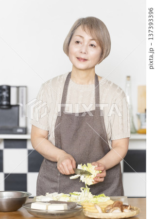 キッチンで野菜を切り料理の下ごしらえをするシニア女性 137393396