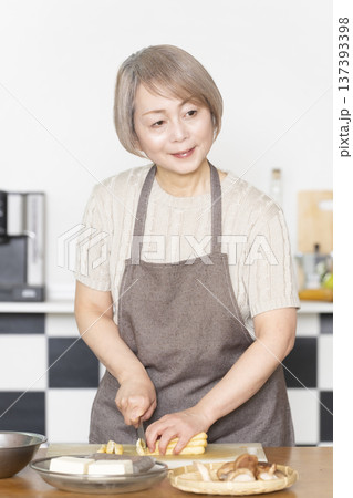 キッチンで野菜を切り料理の下ごしらえをするシニア女性 137393398