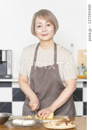 キッチンで野菜を切り料理の下ごしらえをするシニア女性 137393400