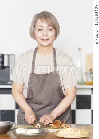 キッチンで野菜を切り料理の下ごしらえをするシニア女性 キッチンで野菜を切り料理の下ごしらえをするシニア女性 137393405
