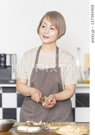 キッチンで野菜を切り料理の下ごしらえをするシニア女性 137393408