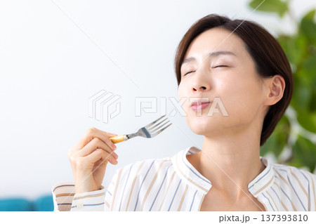 食事　美味しそうに食べている女性 137393810