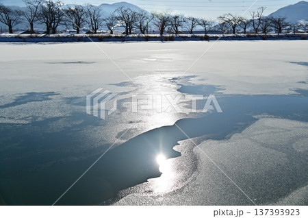 凍結した池の水面に輝く陽の光 137393923