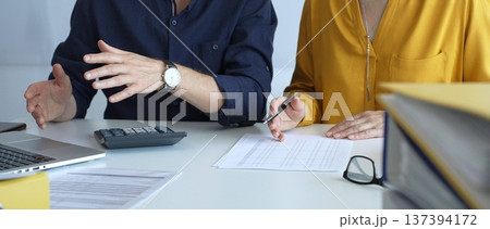 Professional accountants working in a well lit office, analyzing financial data and reviewing statements with a calculator and pen. Audit and taxes theme in business Professional accountants working in a well lit office, analyzing financial data and reviewing statements with a calculator and pen. Audit and taxes theme in business 137394172