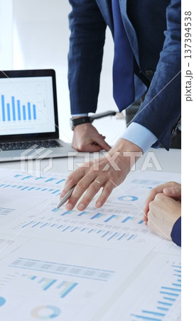 Businessman standing above the table and pointing into financial charts while discussing financial data, market trends during a corporate meeting in office. Business people concept Businessman standing above the table and pointing into financial charts while discussing financial data, market trends during a corporate meeting in office. Business people concept 137394538