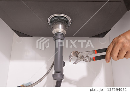 Plumber open trap to fixing drain clog under sink. 137394982