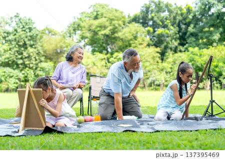Asian senior manl ook and take care two little girl draw or painti during the girl draw or paint and senior woman also sit beside in public park during holiday happy family time. Asian senior manl ook and take care two little girl draw or painti during the girl draw or paint and senior woman also sit beside in public park during holiday happy family time. 137395469