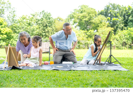 Asian senior manl ook and take care two little girl draw or painti during the girl draw or paint and senior woman also sit beside in public park during holiday happy family time. Asian senior manl ook and take care two little girl draw or painti during the girl draw or paint and senior woman also sit beside in public park during holiday happy family time. 137395470