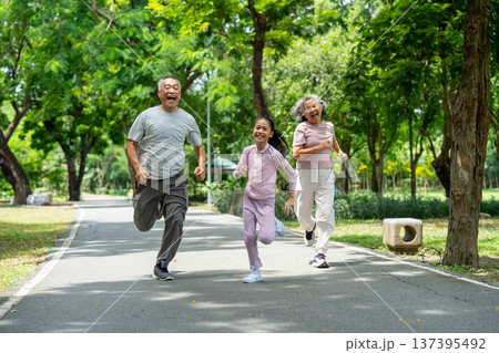 Asian girl run ahead senior man and woman in the competition between them in public park and they look happiness that have good time together. Asian girl run ahead senior man and woman in the competition between them in public park and they look happiness that have good time together. 137395492