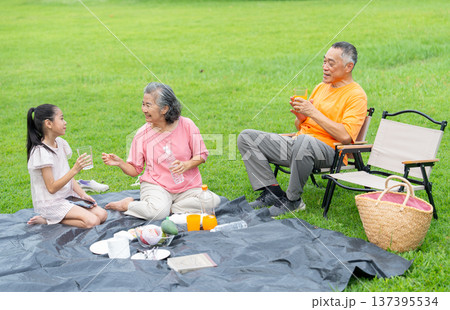 High view of Asian grandmother, grandfather and grandchild enjoy to relax with family together in public park with day light and they look happiness with smiling High view of Asian grandmother, grandfather and grandchild enjoy to relax with family together in public park with day light and they look happiness with smiling 137395534