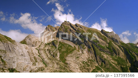 Mountains rise high against blue sky with clouds in the sunny day view of summit and rocky terrain can be seen across the horizon Mountains rise high against blue sky with clouds in the sunny day view of summit and rocky terrain can be seen across the horizon 137395566