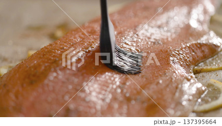 Cooking salmon by brushing it with seasoning in a kitchen with fresh ingredients on the counter Cooking salmon by brushing it with seasoning in a kitchen with fresh ingredients on the counter 137395664