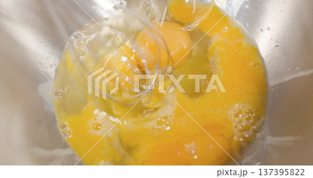 Mixing eggs in a bowl for cooking in a kitchen setting during daytime hours 137395822