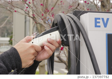 EV充電プラグを接続するドライバーの手元 137397782