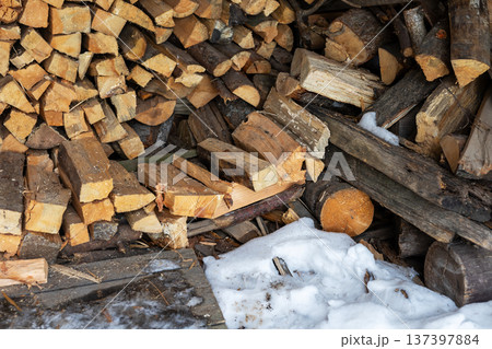 Firewood on melting snow scene. Firewood arrangement amidst melting snow with rustic textures 137397884