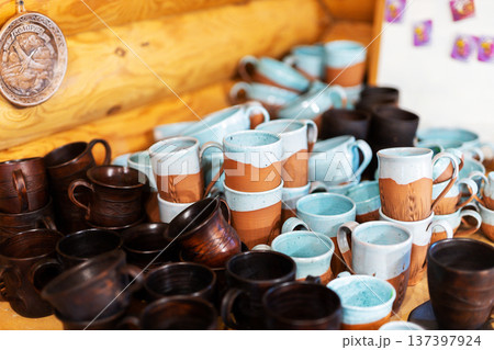 Handpicked glazed ceramic mugs are attractively presented on rustic wooden display for sale 137397924