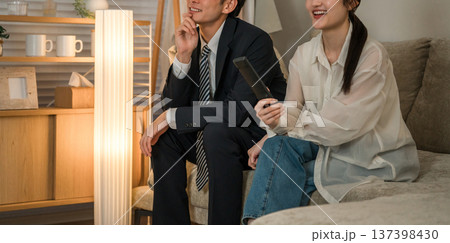夜にリビングのソファに座りテレビを見る夫婦 137398430