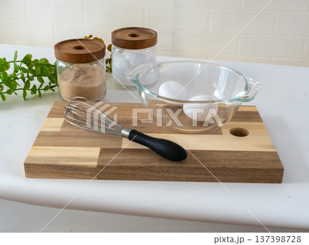 まな板の上の泡立て機とボウルに入った卵 137398728