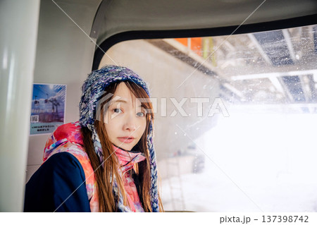 スキー場でゴンドラに乗っている若い女性 スキー場でゴンドラに乗っている若い女性 137398742