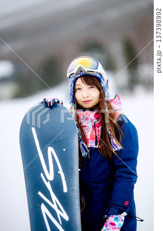 スキー場のゲレンデでウィンタースポーツのスノーボードを楽しむ若い女性 137398992